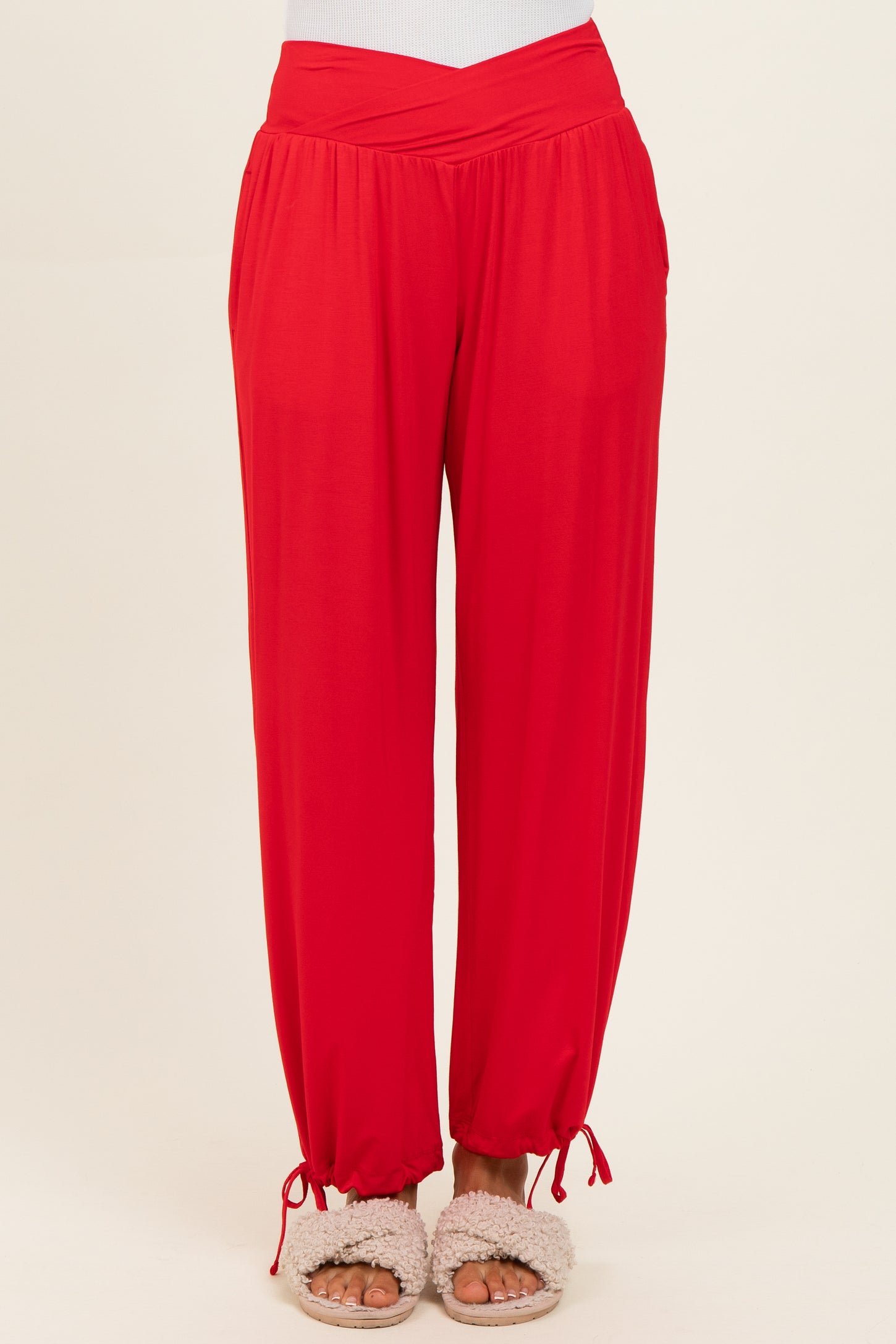 woman wearing red wide-leg pants with a wrapped waist and elastic cuffs, paired with fluffy slippers