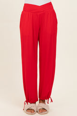 woman wearing red wide-leg pants with a wrapped waist and elastic cuffs, paired with fluffy slippers