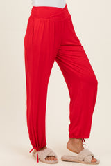 woman wearing red loose-fit jogger pants with elastic waistband and cinched ankles, paired with fuzzy slippers