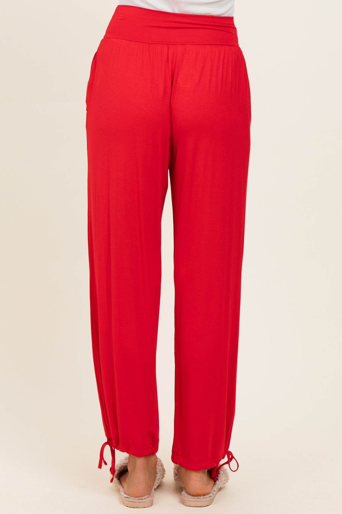 woman wearing red relaxed fit pants with an elastic waistband and drawstring hem details