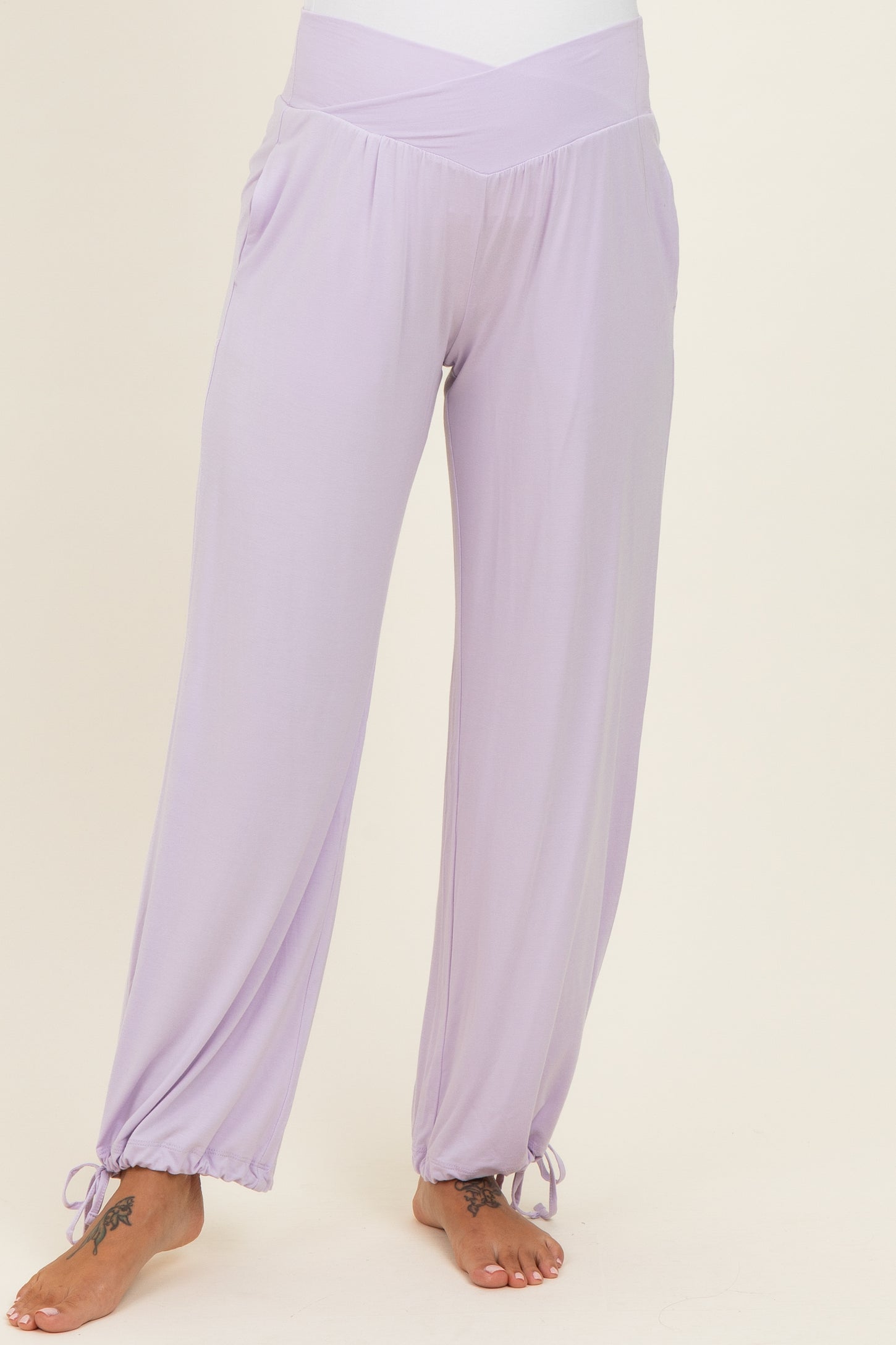 woman wearing light purple maternity pants with a cross-over waistband and gathered cuffs
