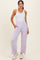 woman wearing a white tank top and lavender high-waisted joggers with pockets and adjustable hems