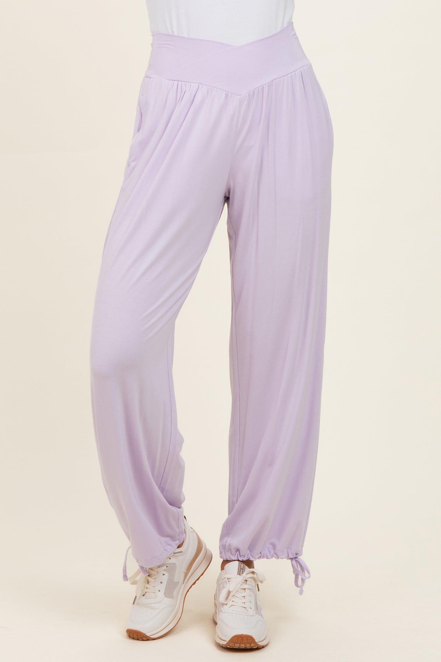 woman wearing lavender casual pants with a high waist and cinched ankle cuffs, paired with white sneakers