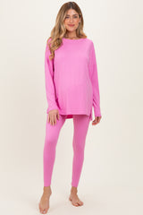 woman wearing a bright pink long sleeve maternity top and matching leggings, showcasing her baby bump