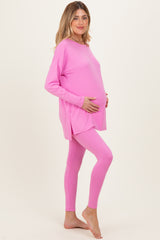 woman wearing a pink long sleeve maternity top and matching leggings, displaying her baby bump