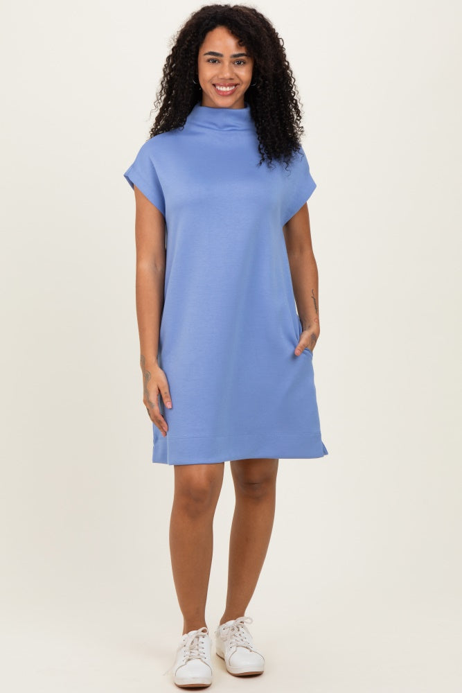 woman wearing a short sleeve light blue shift dress with a high collar and side pockets