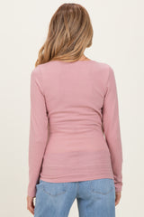 woman wearing a light pink long sleeve maternity top with a fitted style, viewed from the back