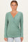 woman wearing a green long sleeve wrap top with a v-neckline and fitted style