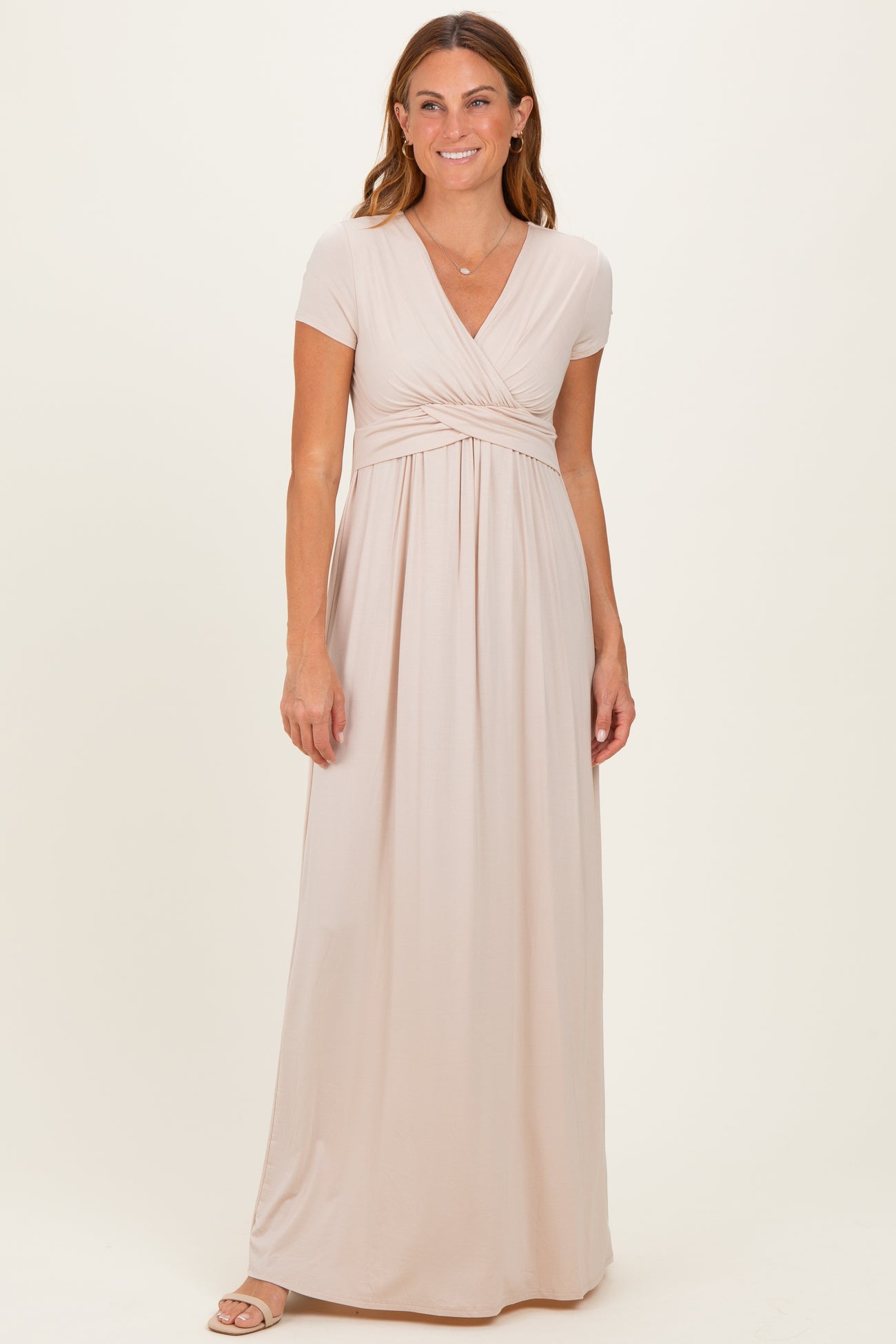 woman wearing a light beige short sleeve maxi dress with a wrap front and empire waist