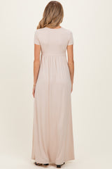 woman wearing a light pink short sleeve maternity maxi dress, showing waistline and flowing skirt from the back