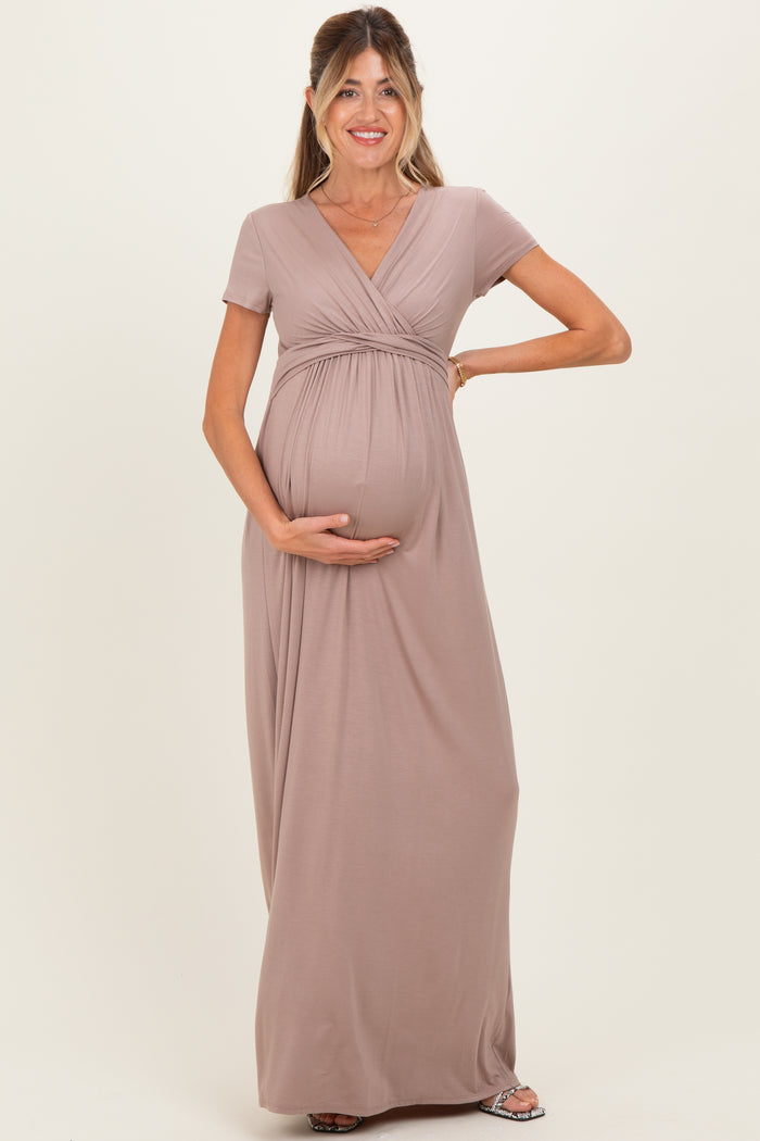 woman wearing a taupe short sleeve maternity maxi dress and holding her baby bump