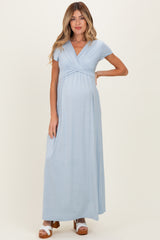 woman wearing a light blue maternity maxi dress with a wrapped bodice and short sleeves, showing her baby bump