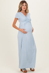 woman wearing a light blue short sleeve maternity maxi dress and holding her baby bump