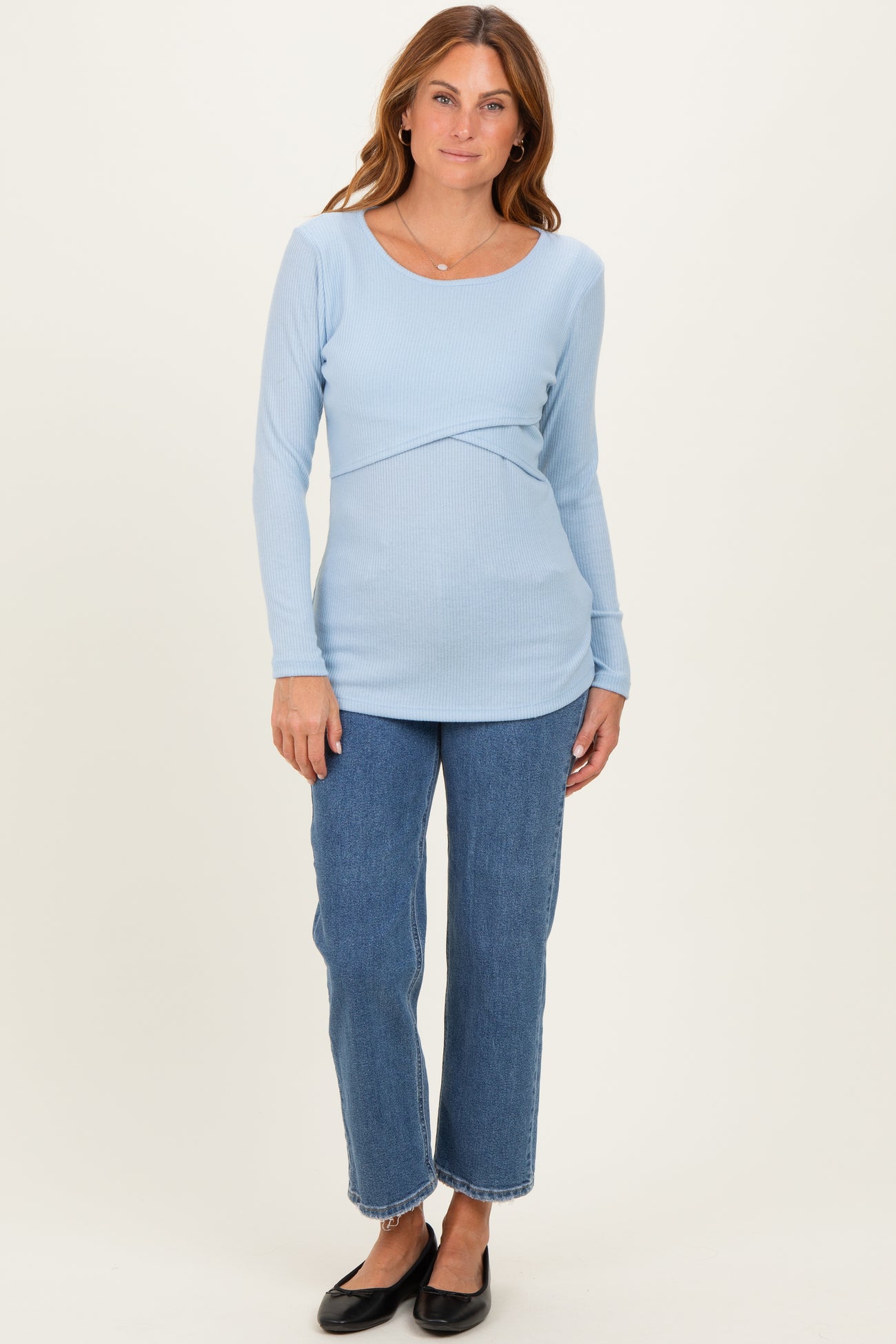 woman wearing a light blue long sleeve ribbed top with a scoop neckline and paired with high-waisted jeans