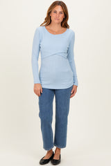 woman wearing a light blue long sleeve ribbed top with a scoop neckline and paired with high-waisted jeans