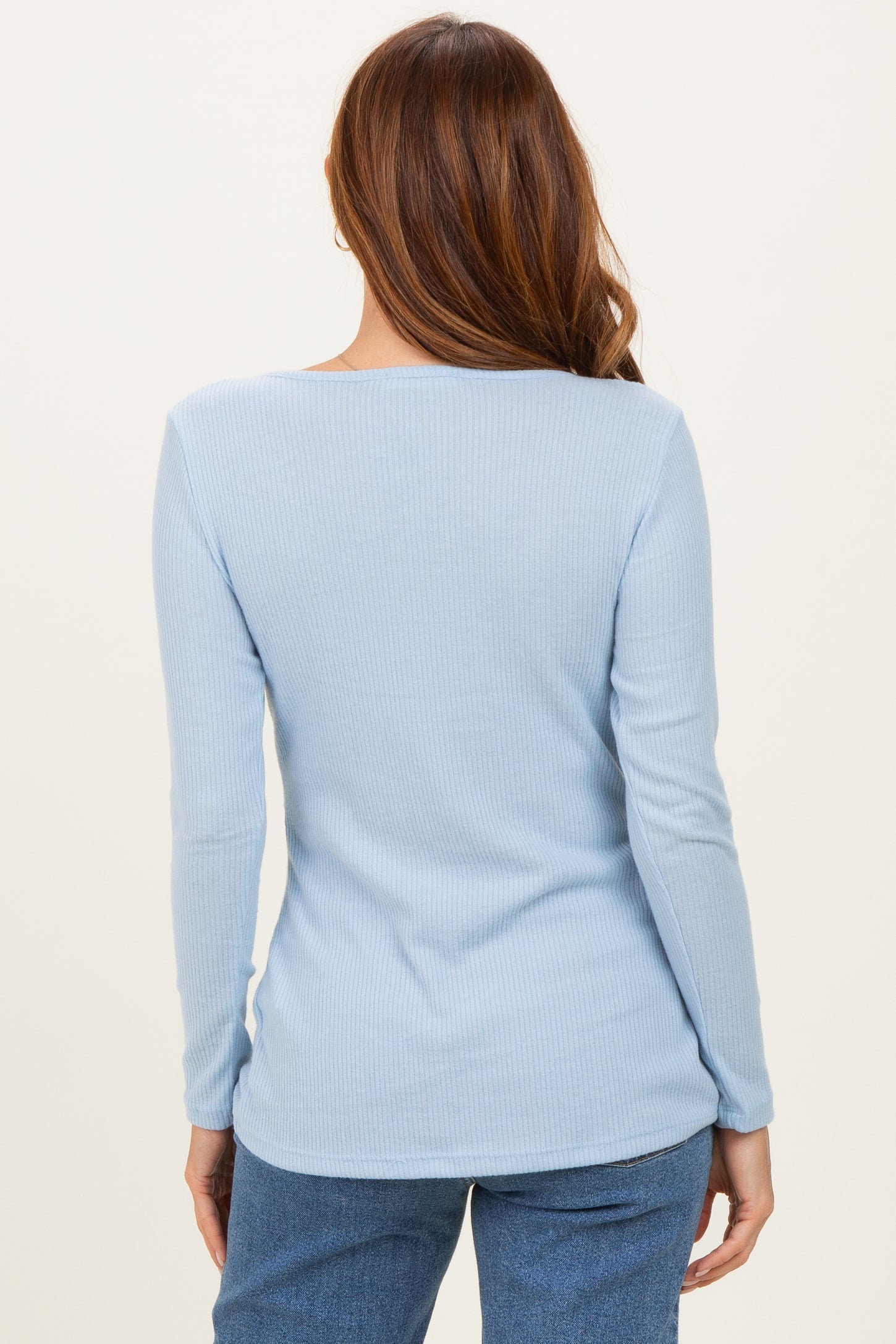 woman wearing a light blue ribbed long sleeve top, viewed from the back