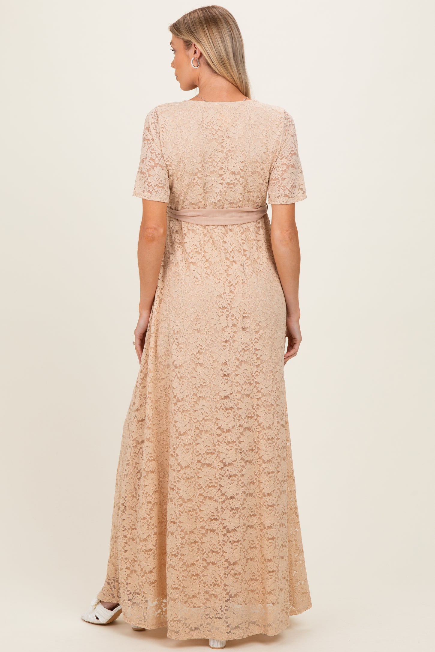 woman wearing a blush lace maternity maxi dress with short sleeves and a fitted waistline, seen from the back