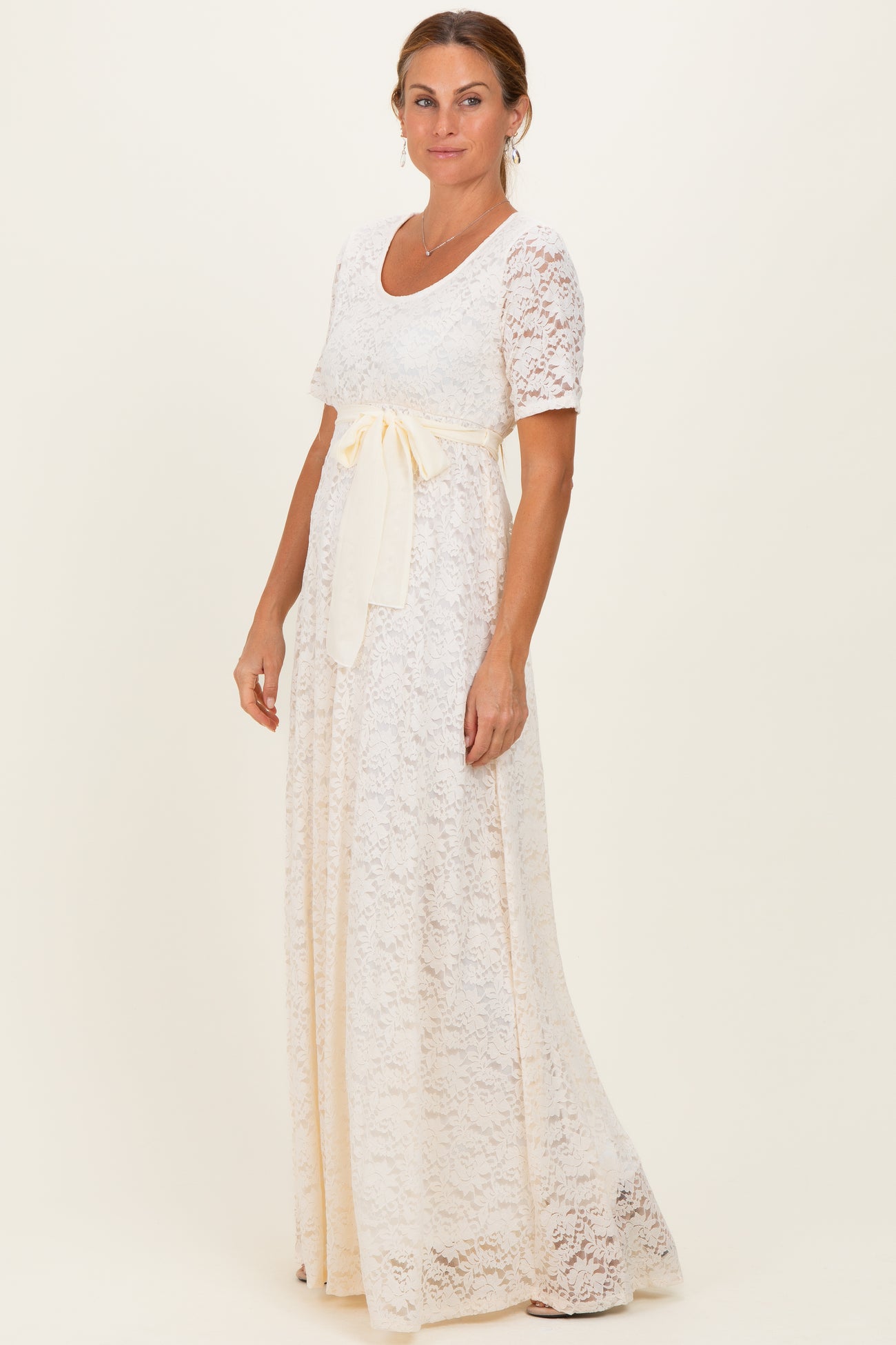 woman wearing a white lace maxi dress with a short sleeve and a yellow ribbon waist tie