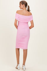 woman wearing a pink off-the-shoulder maternity dress with ruched detailing, showing a fitted silhouette from the back