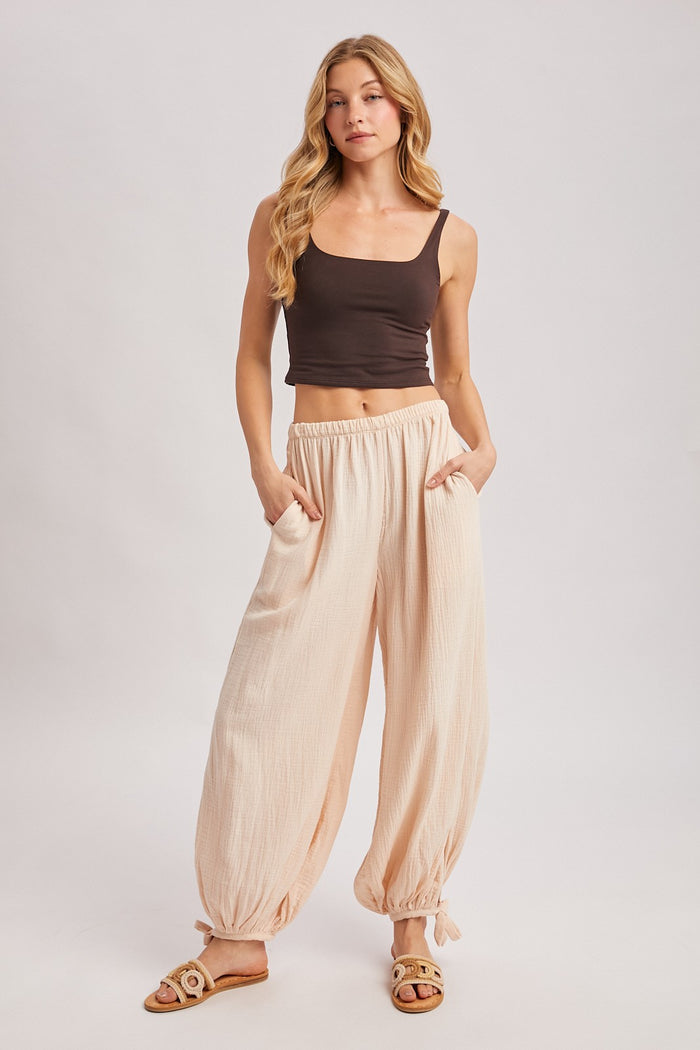 woman wearing a brown cropped tank top and peach balloon pants with pockets