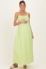 woman wearing a light green maternity maxi dress with smocked bodice and holding her baby bump