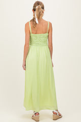 woman wearing a back view of a light green maternity maxi dress with smocked bodice and adjustable straps