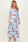 woman wearing a light blue floral maternity maxi dress with three-quarter sleeves and a tie waist, showing her baby bump