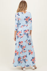 woman wearing a light blue floral maternity maxi dress with three-quarter sleeves and a fitted waistline