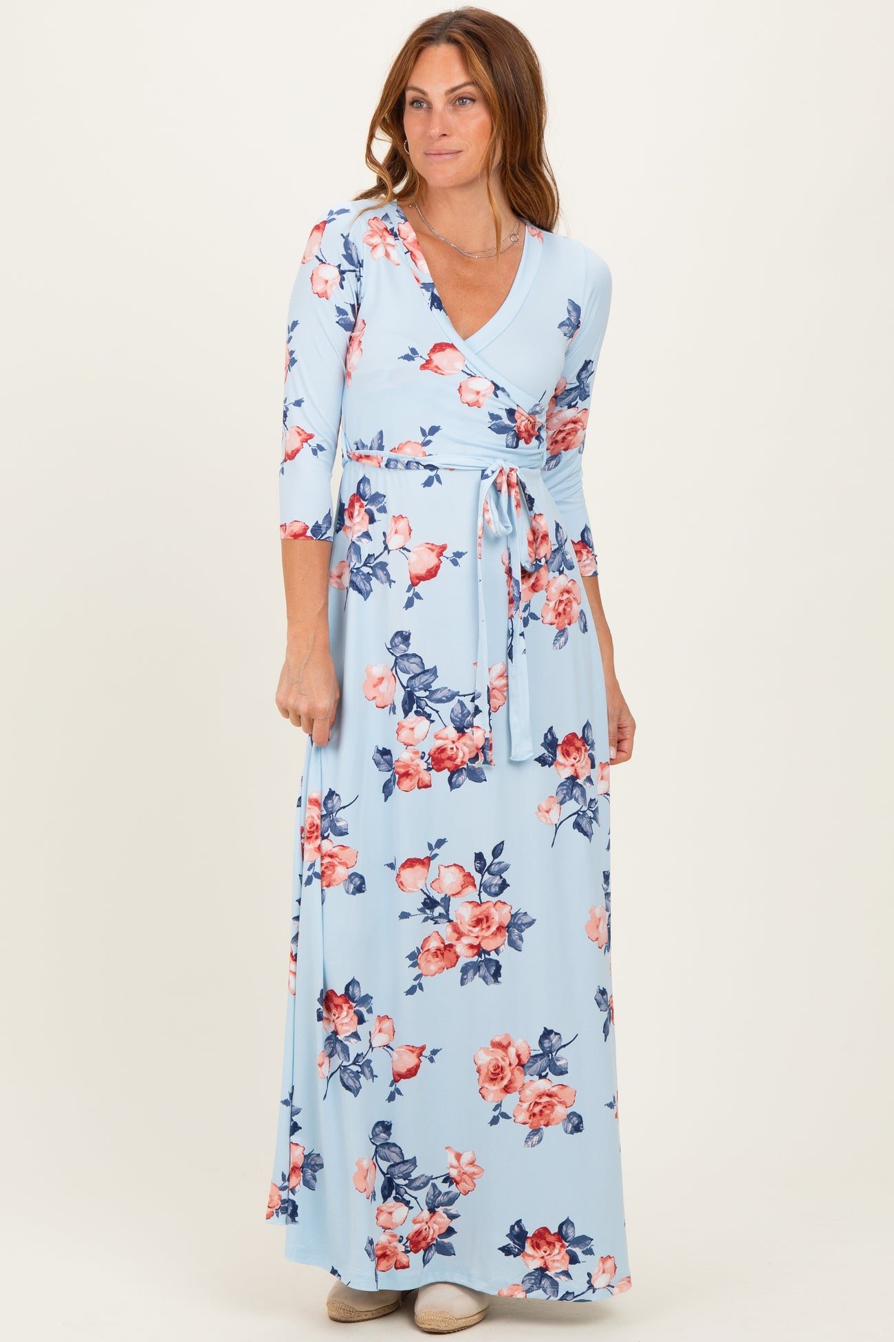 woman wearing a light blue floral wrap maxi dress with three-quarter sleeves and a tie waist