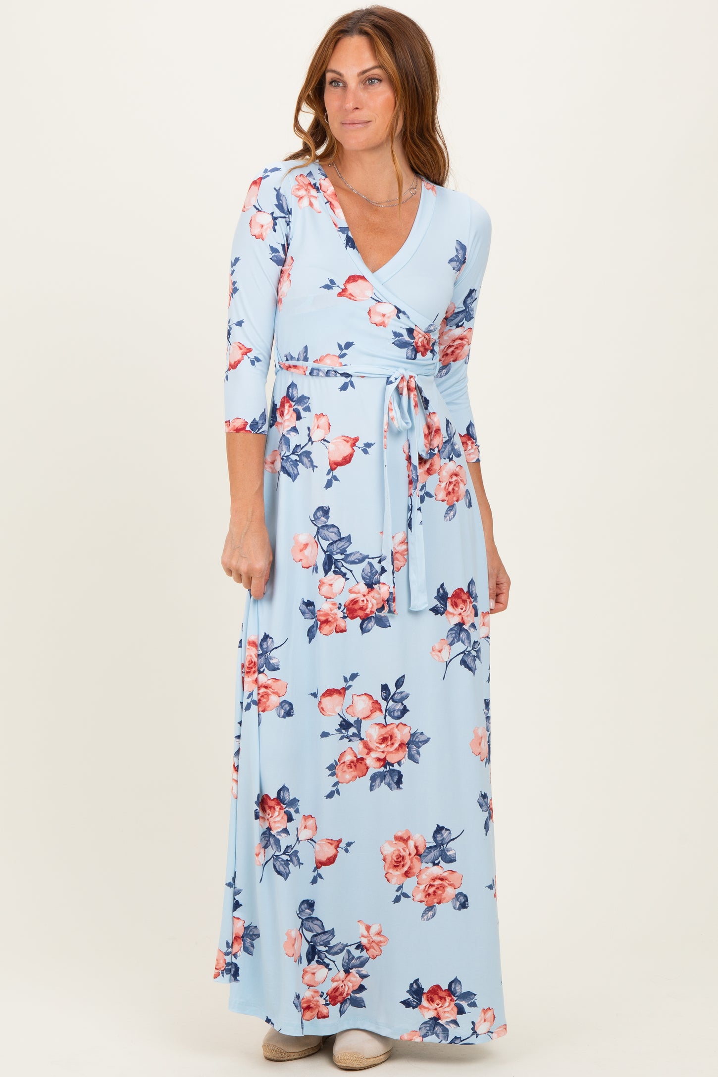 woman wearing a light blue floral wrap maxi dress with three-quarter sleeves and a tie waist