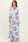 woman wearing a light blue floral wrap maxi dress with three-quarter sleeves and a tie waist
