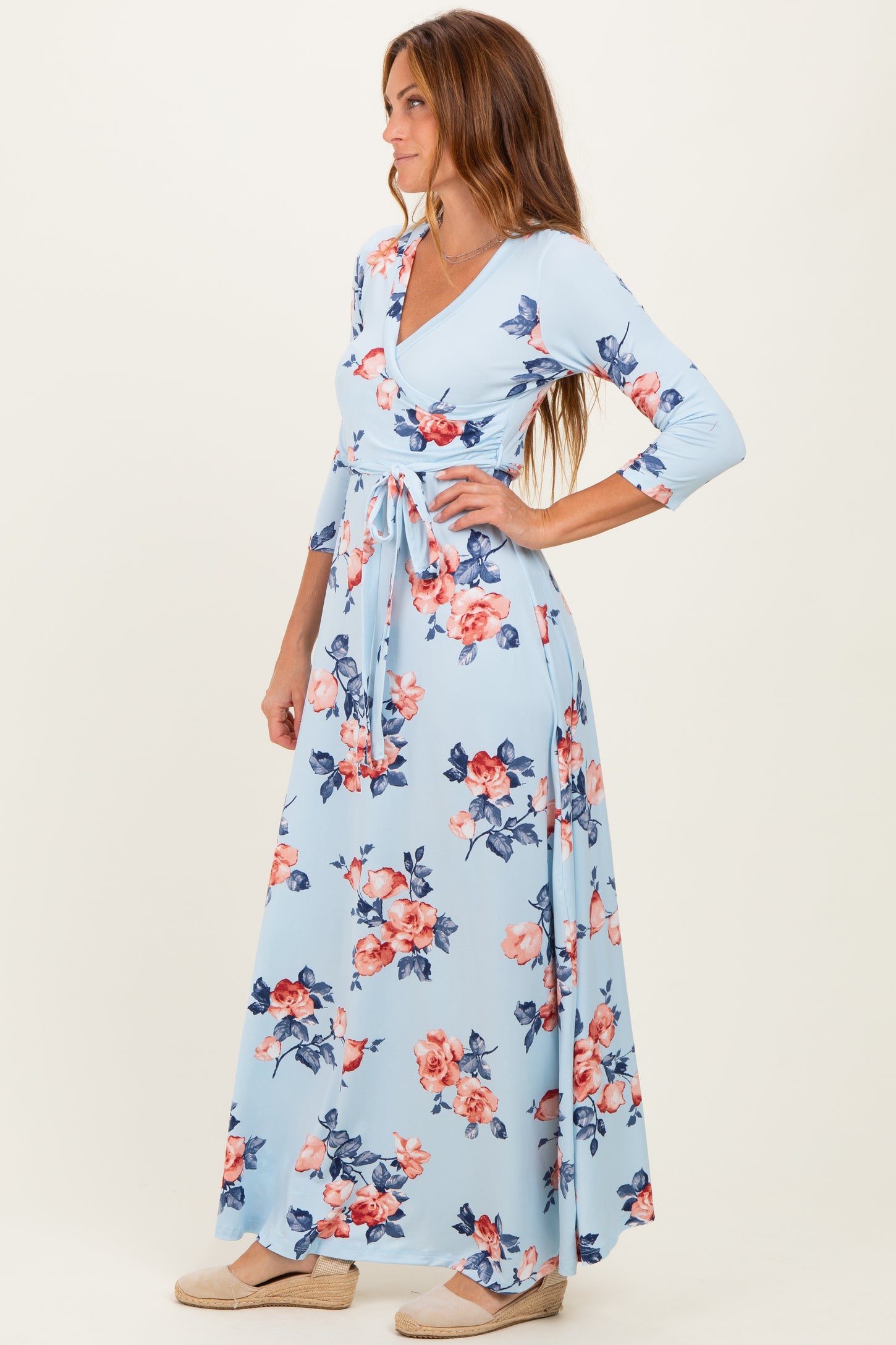 woman wearing a light blue floral maxi dress with long sleeves and a wrap design