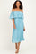 woman wearing a light blue off-the-shoulder pleated dress with ruffle detailing and flowing sleeves