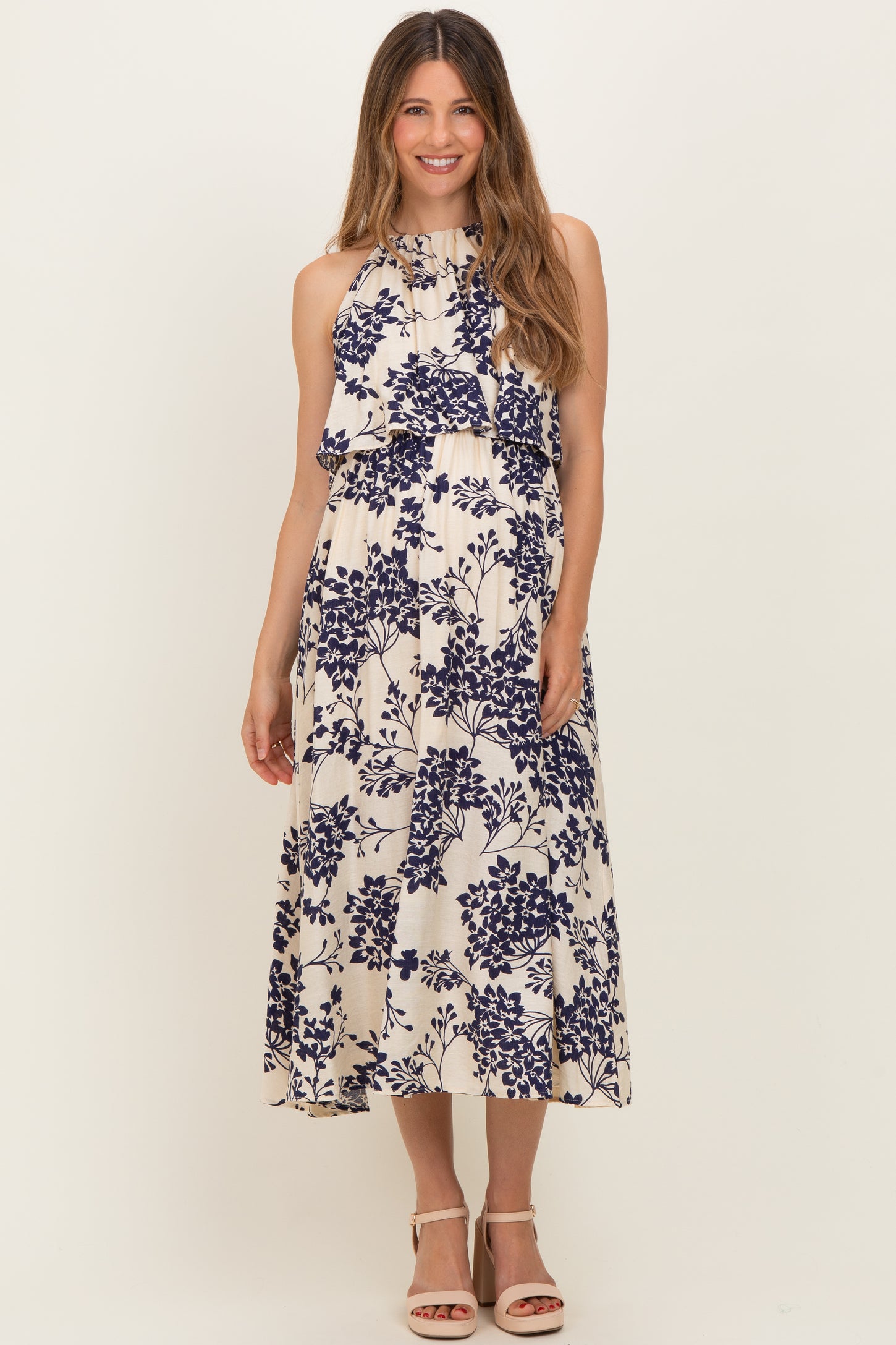 woman wearing a floral print maternity dress with a halter neckline and flowing skirt, showcasing her baby bump