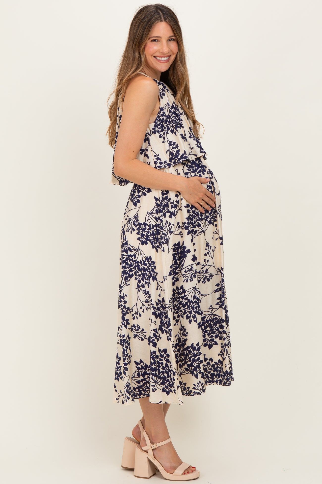 woman wearing a cream floral maternity dress with a flowing silhouette and a visible baby bump