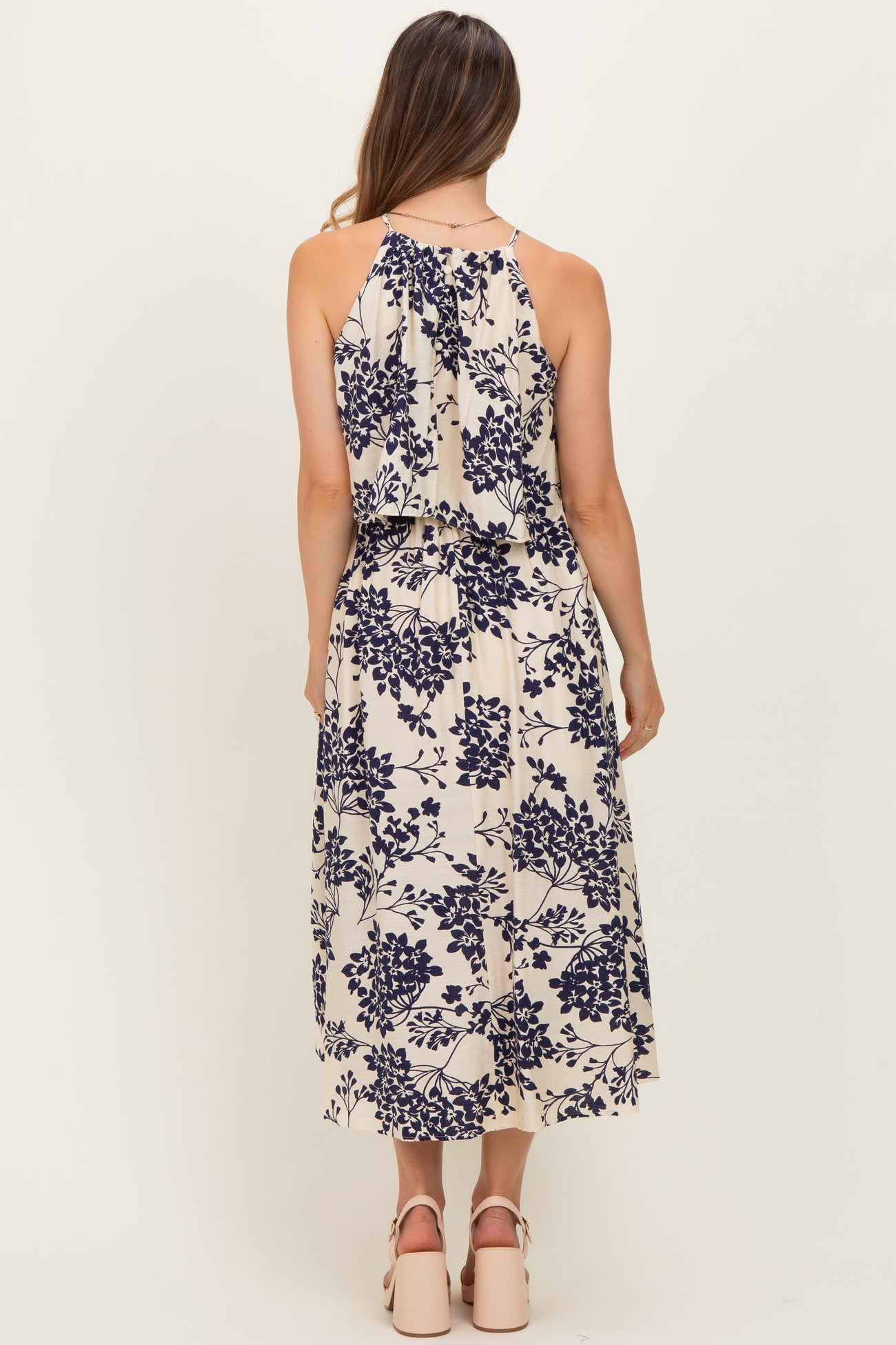 woman wearing a cream floral print maternity dress with a flowing back detail and a relaxed fit