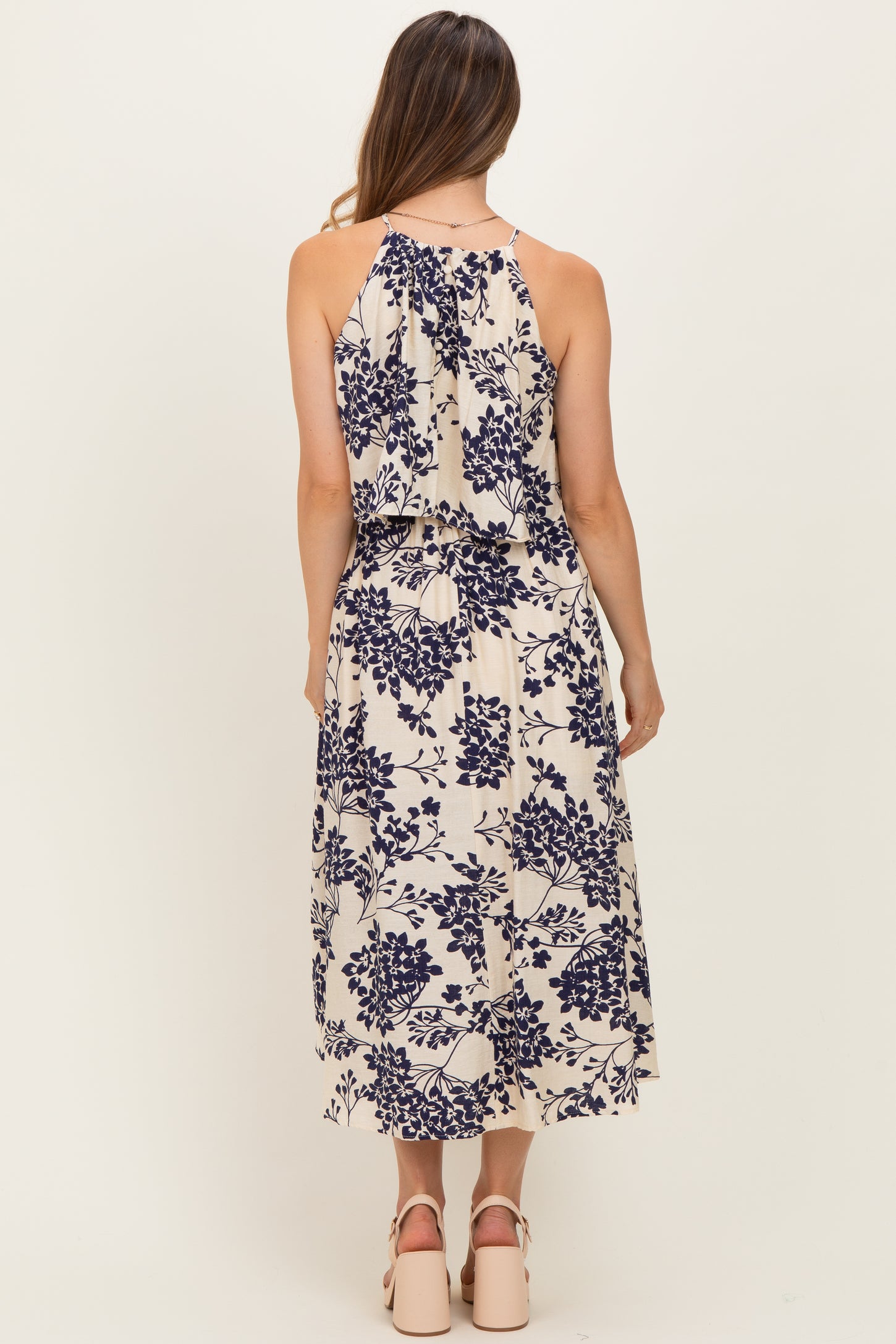 woman wearing a cream floral print maternity dress with a flowing back detail and a relaxed fit