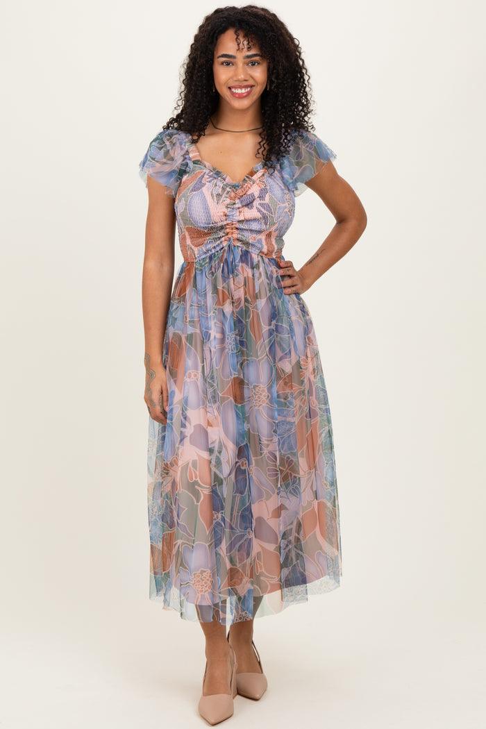 woman wearing a floral sheer maxi dress with puff sleeves and a cinched waist in pastel colors.