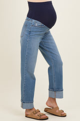 woman wearing a pair of light blue maternity jeans with a navy over-the-bump waistband and rolled cuffs, showing a baby bump