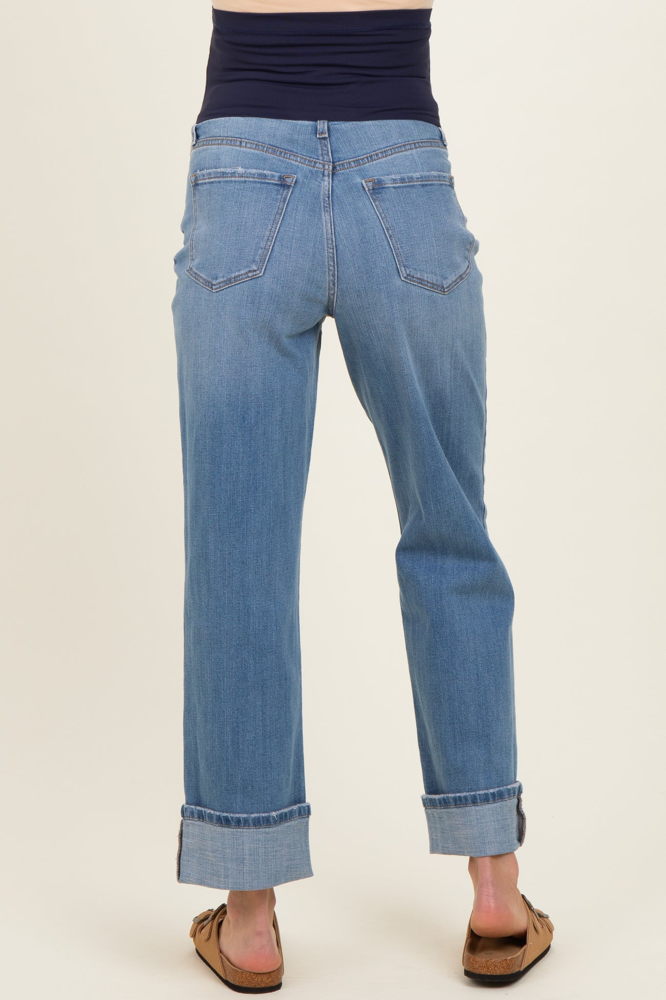 woman wearing light blue maternity jeans with a rolled cuff and a navy blue belly panel, viewed from the back