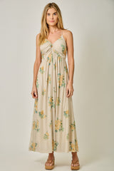 woman wearing a floral print beige maxi dress with a twisted front detail and adjustable spaghetti straps