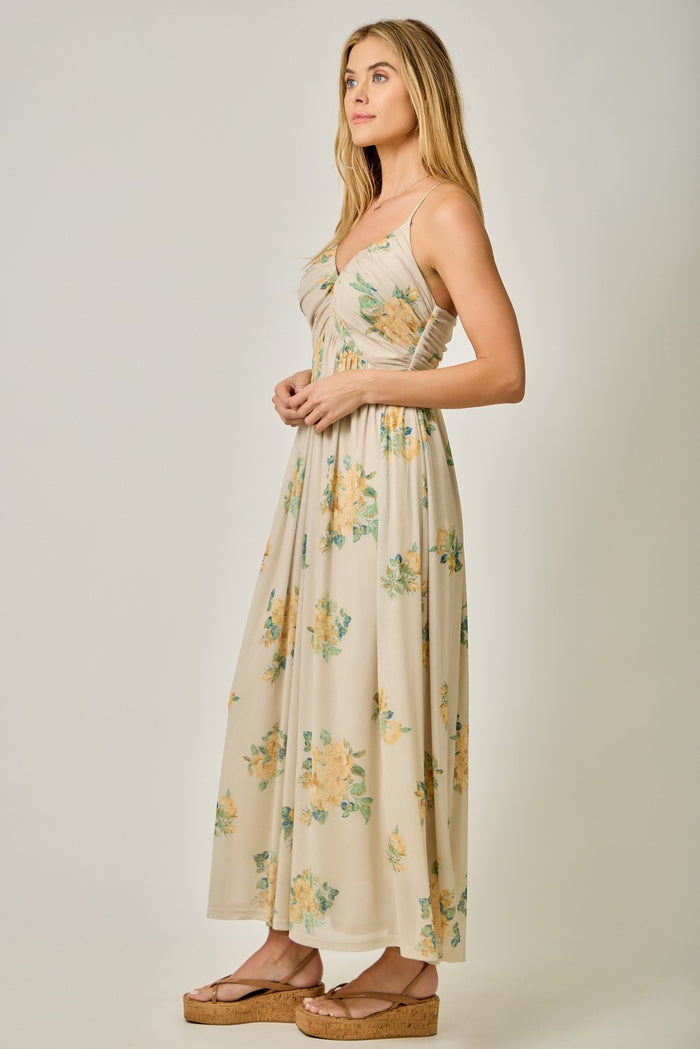 woman wearing a beige floral maxi dress with a fitted bodice and flowy skirt, standing in profile