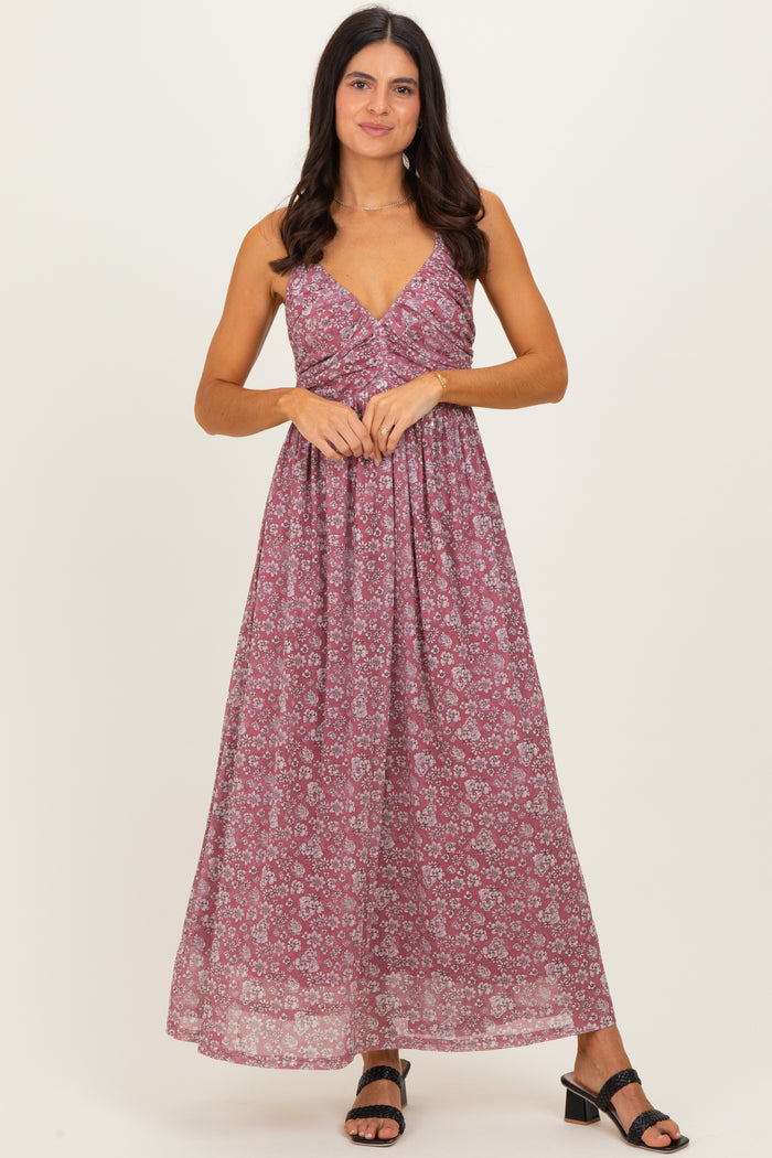 woman wearing a burgundy floral maxi dress with a v-neckline and thin straps, standing and smiling