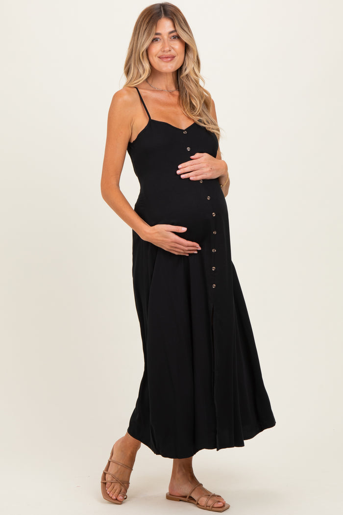 woman wearing a black maternity maxi dress with button details and holding her baby bump