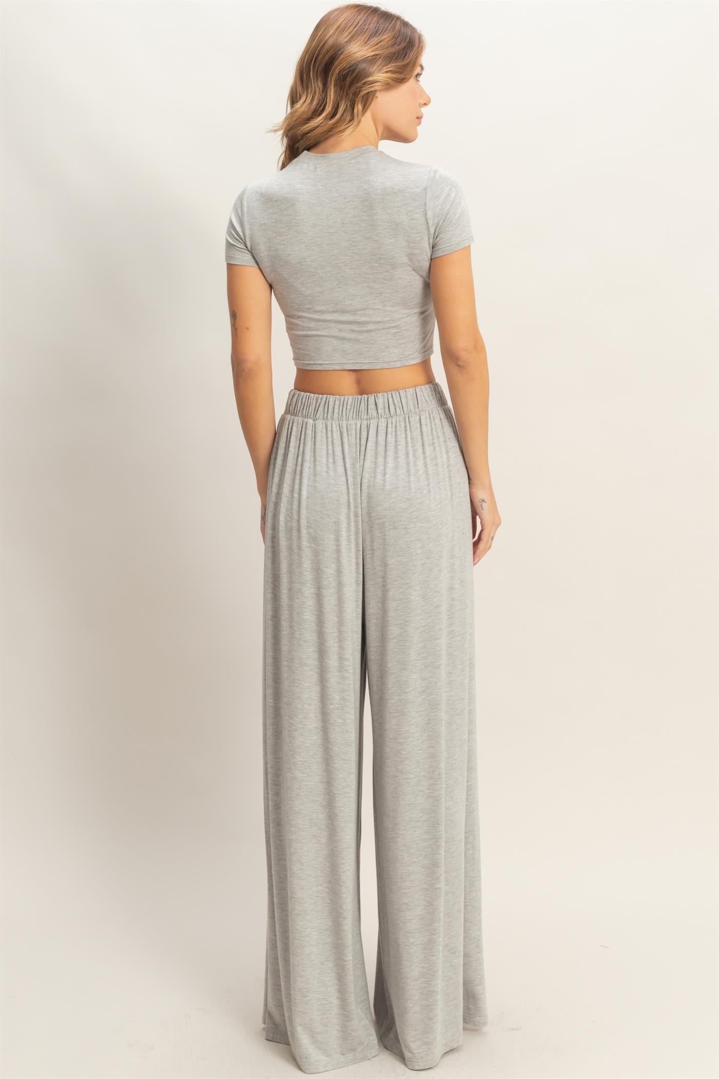 woman wearing a gray cropped top and matching wide-leg pants, viewed from the back