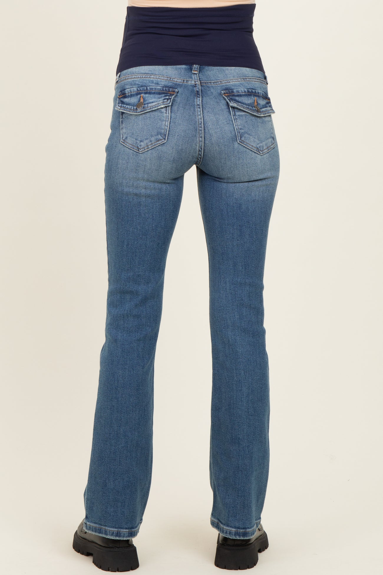 woman wearing light blue maternity jeans from the back with a black waistband and casual footwear