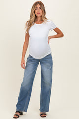 woman wearing a white short sleeve maternity top and distressed light blue wide leg jeans with a visible baby bump