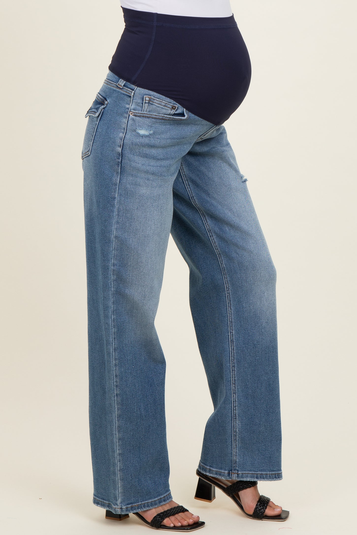 woman wearing light blue maternity wide-leg jeans and showing her baby bump