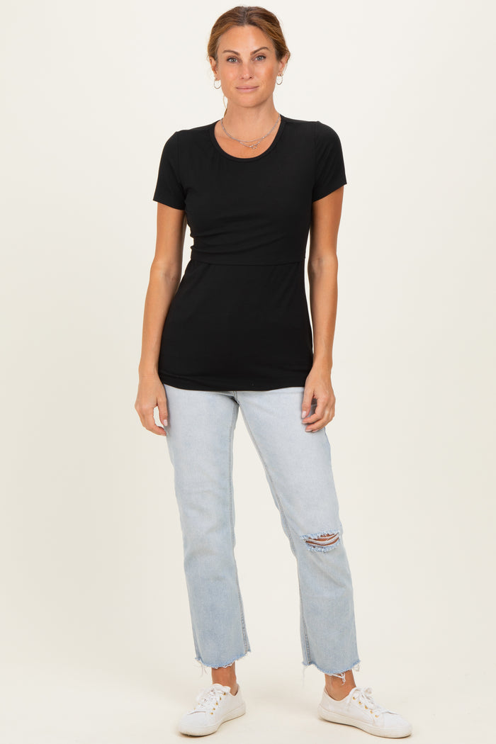woman wearing a black short sleeve top paired with light wash ripped jeans and white sneakers