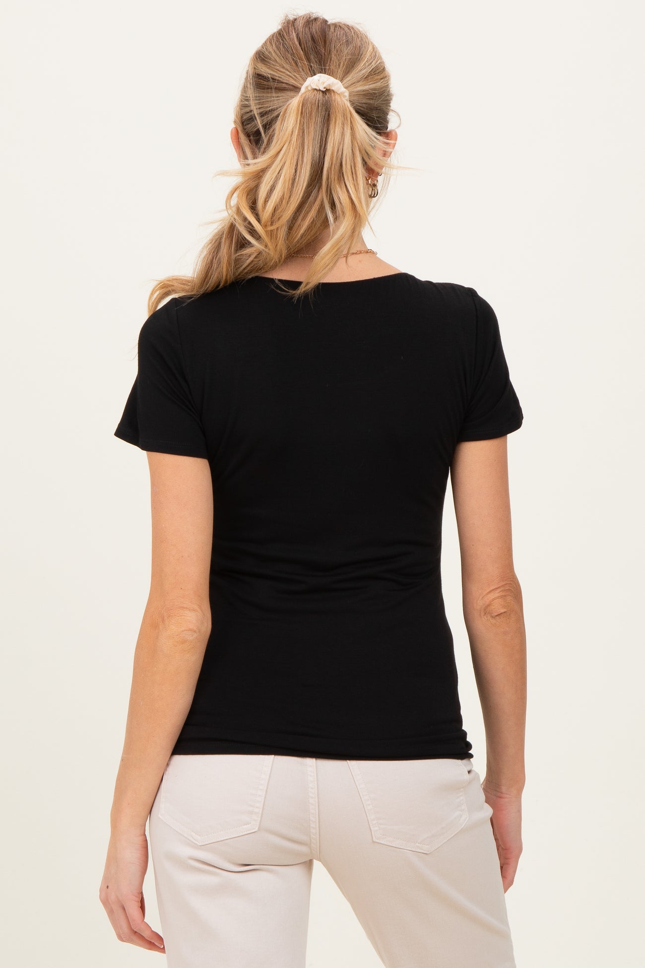 woman wearing a black maternity top viewed from the back, paired with light-colored pants